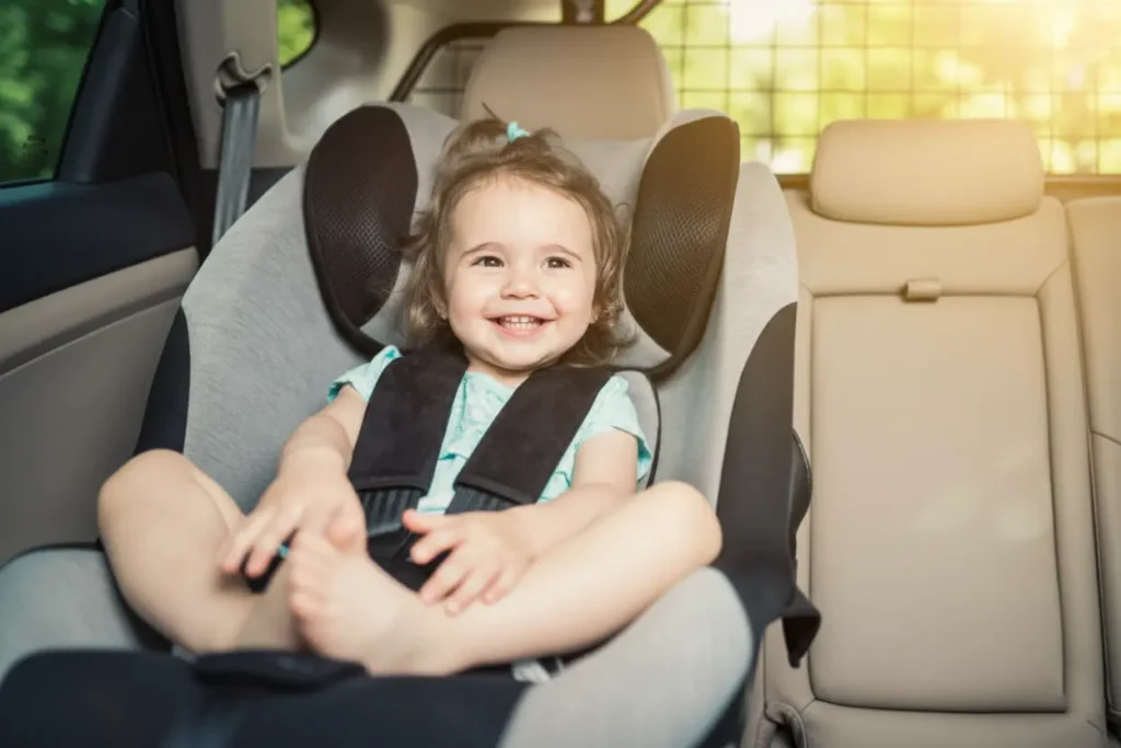 Happy toddler sitting in a car seat during a family road trip in Crete